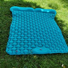 an inflatable mattress is laying on the green grass and it's blue