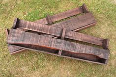 three pieces of wood sitting on top of the grass next to each other in an open area