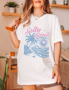 Elevate your beach vibes with our Salty Soul Shirt! This beachy shirt is perfect for any beach bum looking to embrace those ocean inspired vibes. Made for those who live for the summer time, this Salty Beach Shirt exudes a laid-back charm that captures the essence of the sea. Add a touch of coastal cool to your wardrobe with this must-have addition to your collection of beachy shirts! ✧ ABOUT OUR PRODUCTS ✧ For a oversized fit, go up two sizes.- Unisex fit, true to size.- Check the size chart be Blue Beach T-shirt With Front Print, Summer Cotton T-shirt With Palm Tree Print, Trendy White Print T-shirt For Vacation, Casual White T-shirt For Vacation, White Tropical T-shirt For Beach Season, Tropical Graphic Print T-shirt For Beach, White Beach Shirt For Summer, Printed White Tops For Surfing, White Short Sleeve Shirt For Beach