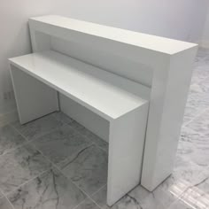 a white bench sitting in the middle of a room next to a wall with marble flooring