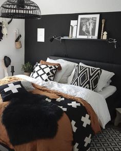 a black and white bedroom with lots of pillows on the headboard, bedding