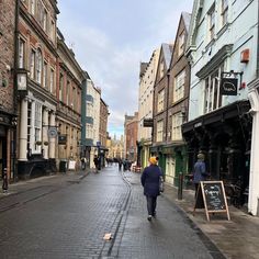 a man walking down the middle of an empty street with buildings in the back ground