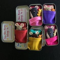 four tins filled with assorted items on top of a black table next to each other