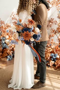 a bride and groom standing next to each other in front of an artistic backdrop with flowers