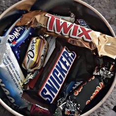 a bowl filled with assorted candy bars and wrappers on top of each other