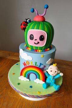 a birthday cake decorated with an animal, rainbow and lady bug theme on top of a wooden table