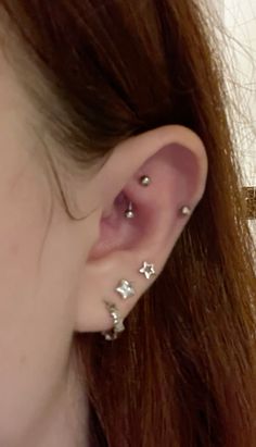 a close up of a person's ear with three piercings on it and one behind the ear