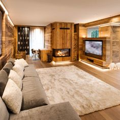 a large living room with wood paneling and white rugs on the hardwood floor