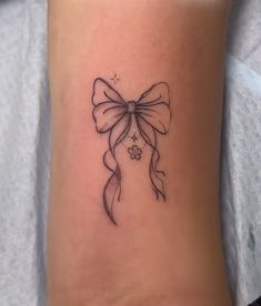 a woman's ankle with a bow tattoo on her left side ribcage