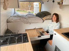 a woman sitting in the back of a camper with her laptop computer on it