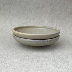 two white bowls sitting next to each other on top of a gray tablecloth covered floor