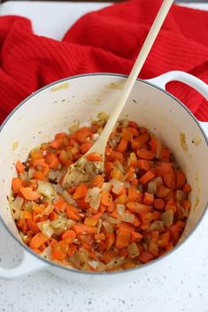 a pot filled with carrots and onions on top of a table