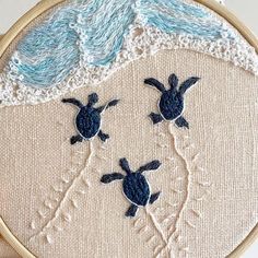 a close up of a embroidery on a piece of cloth with two turtles swimming in the water