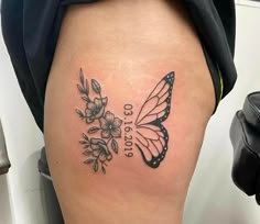 a woman's thigh with a butterfly and flowers tattoo on it