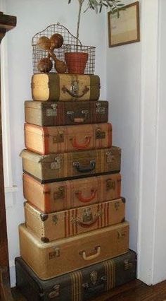 several suitcases stacked on top of each other in front of a wall with a potted plant