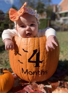 a baby sitting in a pumpkin with the number four on it