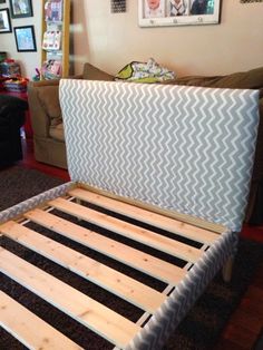 a bed frame made out of wooden slats in a living room with couches and pictures on the wall