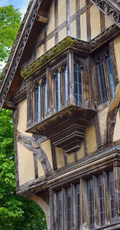 an old wooden and stucco building with lots of windows on the top floor, surrounded by trees