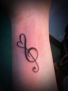 a musical note with a heart tattoo on the left forearm and right hand is shown in black ink