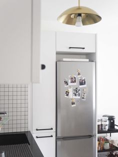 a stainless steel refrigerator with magnets on the door in a white and black kitchen