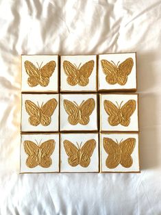 six gold butterfly coasters sitting on top of a white sheet