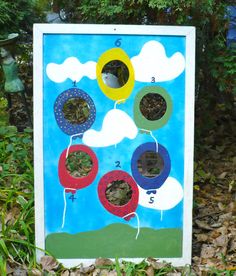 a blue board with circles and numbers on it in the grass next to some trees