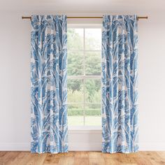 a blue and white curtain hanging in front of a window next to a wooden floor