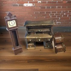 an old wooden desk and chair with a clock on the top, sitting next to a brick wall