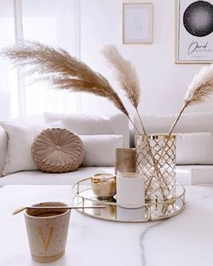 a living room with white couches and decorative items on the coffee table in front of it