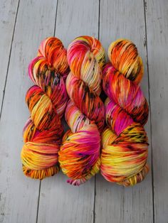 several skeins of multicolored yarn sitting on a wooden floor next to each other