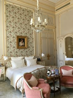 a bedroom with floral wallpaper and chandelier above the bed is decorated in pink