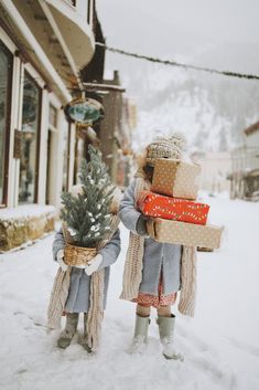 two children carrying presents in the snow on their back legs, one holding a christmas tree