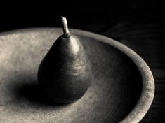 a black and white photo of a pear in a bowl