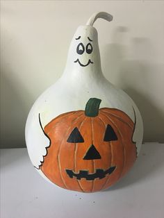 a white pumpkin shaped like a ghost sitting on top of a table next to a wall