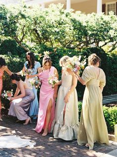 a group of women standing next to each other in front of trees and shrubbery