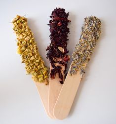 three wooden spoons filled with different types of herbs