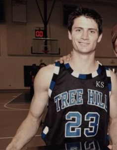 two young men standing next to each other on a basketball court