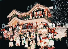 a group of people standing in front of a house covered in christmas lights