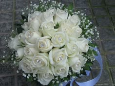 a bridal bouquet with white roses and baby's breath on a brick floor