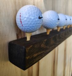 three golf balls sitting on top of a wooden shelf