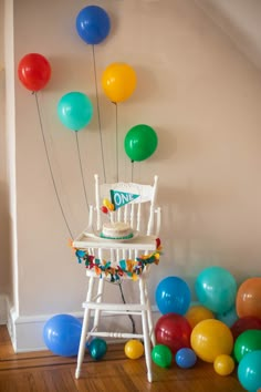 a birthday cake sitting on top of a chair surrounded by balloons