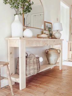 a wooden table with baskets and vases on it in a white living room area