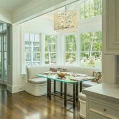 a dining room table and bench in front of large windows