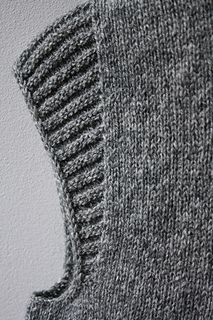 a gray knitted sweater hanging on the wall