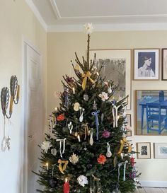 a decorated christmas tree in the corner of a room with pictures on the wall behind it