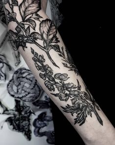 a woman's arm with flowers and leaves tattooed on the left side of her arm