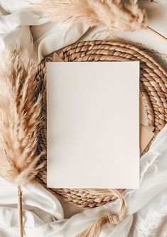 an empty white card sitting on top of a wicker basket next to some feathers