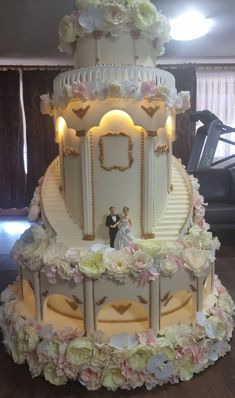 a wedding cake is decorated with white flowers and gold trimmings on a table