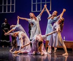 a group of young women standing on top of a stage holding hands in the air