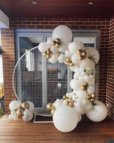 white and gold balloons are hanging from the side of a brick wall in front of a window